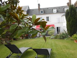 twee stoelen en een boom in een tuin met een huis bij LE RELAIS DU BON'EURE in Évreux