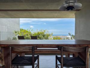 a wooden table with two chairs and a view of the ocean at 大木の宿 Shicari in Yomitan