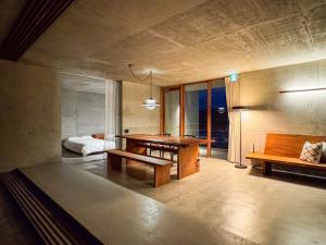 a room with a table and benches and a bed at 大木の宿 Shicari in Yomitan