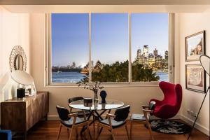 a living room with a table and chairs and a large window at Opera House Retreat - Opera House & Bridge View in Sydney