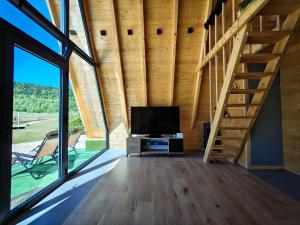 a living room with a tv and a staircase at Wolf Ridge Mountain Cabin Montenegro in Plužine