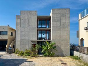 a concrete house with large windows on a street at 大木の宿 Shicari in Yomitan