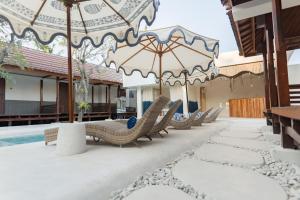 a row of chairs and umbrellas next to a pool at Maresia in Gili Islands