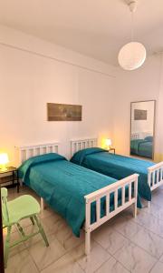 a bedroom with two beds and a green chair at Miramare Apartment in Ancona