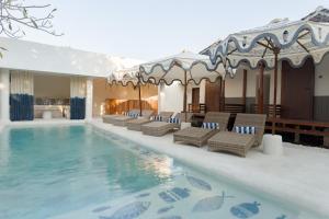 a hotel swimming pool with chairs and a table at Maresia in Gili Islands