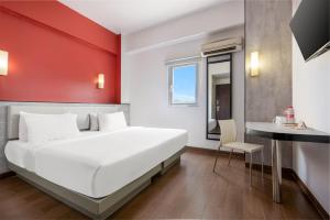 a bedroom with a white bed and a red wall at Amaris Hotel Pekanbaru in Pekanbaru