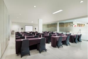 a conference room with tables and chairs and a screen at Amaris Hotel Pekanbaru in Pekanbaru