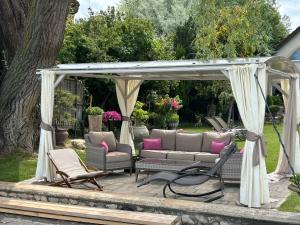 a gazebo with a couch and chairs on a patio at Viktoria House in Balatonszárszó