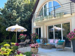 a patio with a couch and an umbrella and chairs at Viktoria House in Balatonszárszó +33 photos