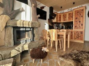 a living room with a stone fireplace and a table at Domki Pod Góralskim Niebem in Zakopane