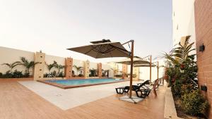 a pool with chairs and an umbrella next to a building at Hôtel Mandela Nouakchott in Nouakchott