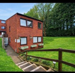 a red brick house with windows on a green field at 1 Bed Apartment Sleeps 2 -Free Parking -WiFi & Tv in Sutton Coldfield