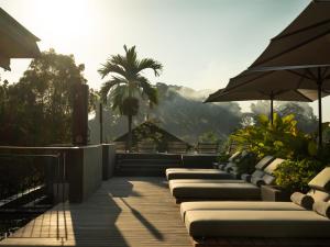 a row of lounge chairs with umbrellas on a deck at Alaya Suites Ubud in Ubud