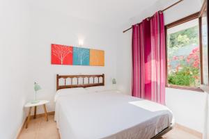 a white bedroom with a bed and a window at Holiday Home Marina 9 in Portals Nous