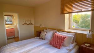 a bedroom with a white bed with pillows and a window at Les Prés du Manoir in Le Manoir