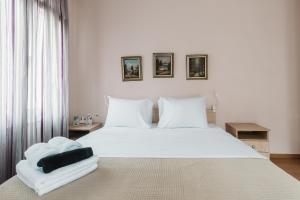 a white bedroom with a large white bed with white pillows at Angelikis Maisonette in Kastoria