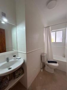a bathroom with a sink and a toilet and a mirror at Marenga in El Rompido +18 photos