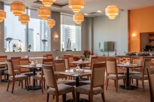 a restaurant with tables and chairs and large windows at Fraser Suites Seef Bahrain in Manama