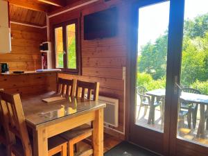 a dining room with a table and a window and a patio at Résidence Les Dômes in Murol