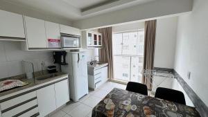 a small kitchen with a table and a refrigerator at CRCN - Evian Thermas Residence in Caldas Novas
