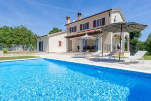 a villa with a swimming pool in front of a house at Villa Andretti in Gračišće
