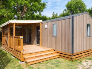a wooden cabin with a deck in the grass at Camping Pegomas in Saint-Rémy-de-Provence