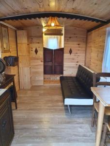 a living room with a black couch in a cabin at roulotte les sabots d Helene in Cruzilles-lès-Mépillat