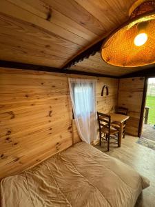 a bedroom in a log cabin with a bed and a table at roulotte les sabots d Helene in Cruzilles-lès-Mépillat