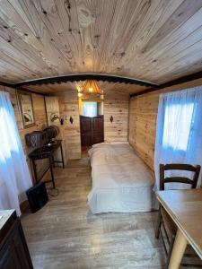 a bed in a room with a wooden ceiling at roulotte les sabots d Helene in Cruzilles-lès-Mépillat