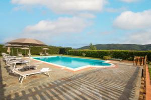 a swimming pool with chairs and an umbrella at La Pietraia by VacaVilla in Poppi