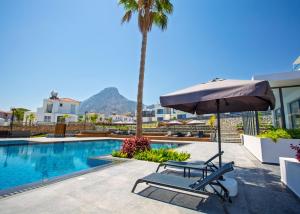 a chair and an umbrella next to a swimming pool at Aqualina C3-4 by HolidayKeys in Kyrenia
