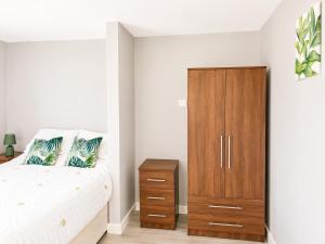 a bedroom with a bed and a wooden cabinet at Dainty Curve in Kettering +5 photos