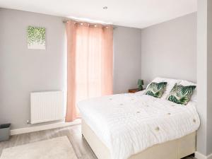 a white bedroom with a large bed and a window at Dainty Curve in Kettering