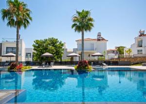 a large swimming pool with palm trees and buildings at Aqualina C3-4 by HolidayKeys in Kyrenia