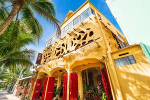 a yellow building with red doors and a palm tree at OXY Cave Homestay Mũi Né in Mui Ne