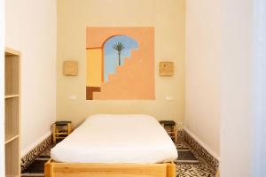 a bedroom with a bed and a painting on the wall at Hostel La Smala in Essaouira