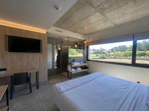 a bedroom with a bed and a desk and a large window at Hotel VIDA Devalar Do Mar in Camariñas