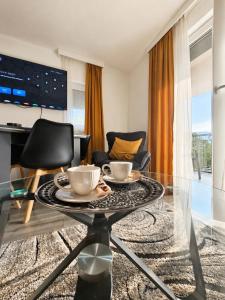 a living room with a glass table with two cups on it at Apartments and Rooms Villa Majestic in Bihać
