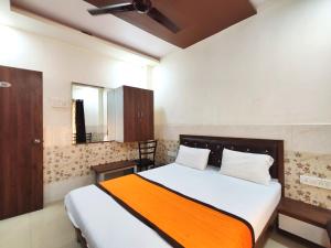 a bedroom with a bed with an orange blanket at Hotel Sagar Residency in Panvel