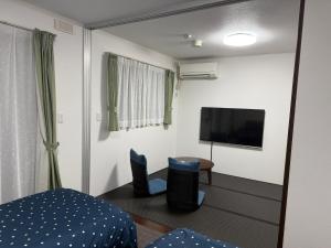 a room with a tv and a bed and chairs at House Nozomi in Kyoto