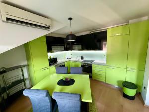 a kitchen with green cabinets and a table with chairs at Lambada Penthouse in Bugojno