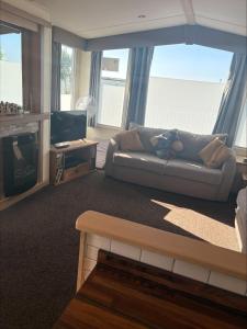 a living room with a couch and a television at Starview 8 berth Caravan in Chapel Saint Leonards