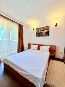 a bedroom with a white bed and a window at Apartament Centru Plaja Modern in Constanţa