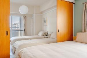 three beds in a room with a window at Cozy Japandi 3LDK in Namba for Groups in Osaka