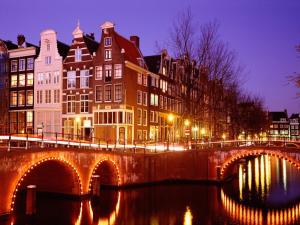 un ponte su un fiume in una città di notte di Mozart Hotel ad Amsterdam