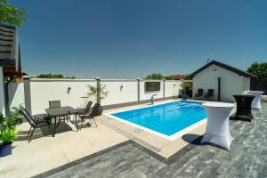 a swimming pool on a patio with a table and chairs at Villa Azure Sea in Bijeljina