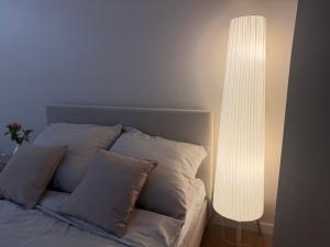 a white bed with pillows and a white lamp at Mazury Mood kawalerka studio in Giżycko