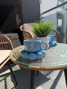 a table with two cups and a potted plant on it at Mazury Mood kawalerka studio in Giżycko