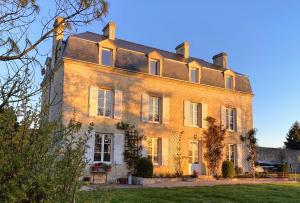 a large brick building with a roof at Les Prés du Manoir in Le Manoir