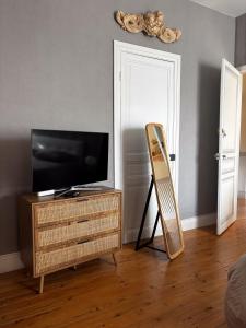 a living room with a television and a wooden dresser at Chez Marie in Dunkerque